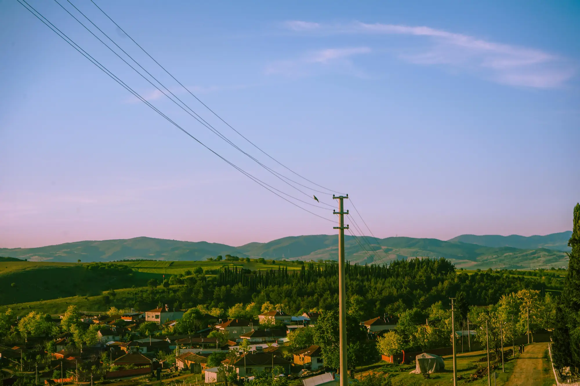 A hillside village with a distribution line running in on wooden poles, at dusk